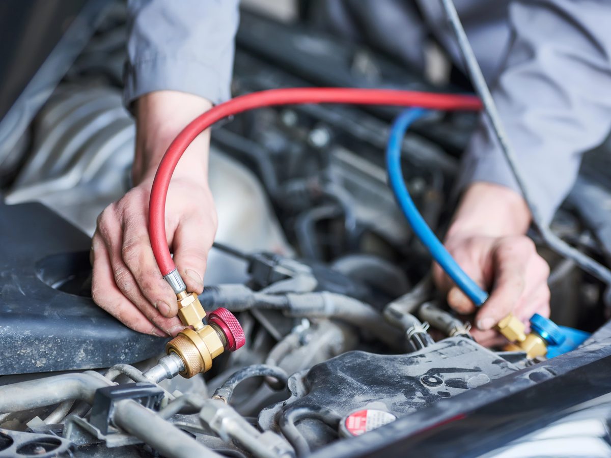 Technician connecting A/C service gauges to a car